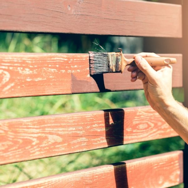 person staining a wood fence