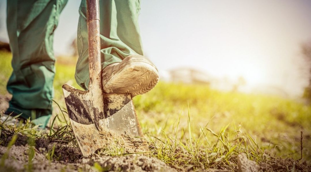 man outdoors digging in backyard to install a dog containment fencing company